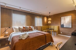 Une chambre d’hôtel moderne avec un grand lit, un bureau, une chaise et une petite table.