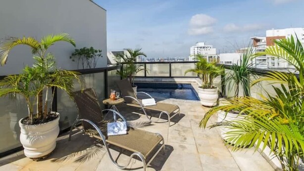 Une terrasse sur le toit avec une piscine, des chaises longues et des plantes en pot.