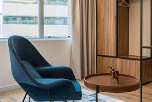 Une pièce moderne avec une chaise bleue, une petite table ronde et une étagère en bois.