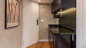 Uma cozinha moderna com bancada preta, pia de aço inoxidável e painel de azulejos.