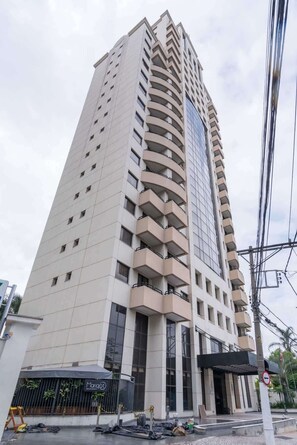 A tall, modern hotel with a curved facade, multiple balconies, and a restaurant at the ground level. - #QL1301 | Cyclinn Faria Lima Pinheiros (Pinheiros)