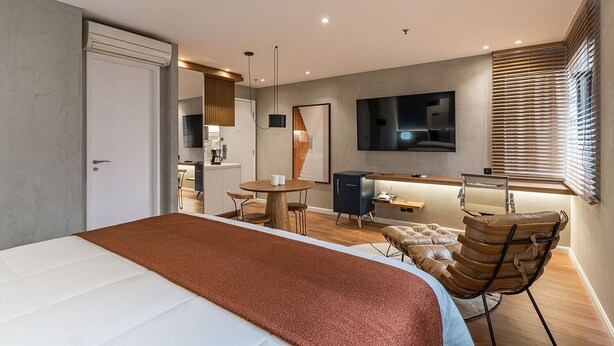 Una camera da letto moderna con un letto grande, una scrivania, una sedia e una televisione.