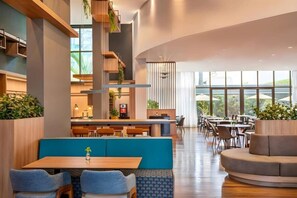 Un intérieur moderne avec un bar central, des espaces salon et de grandes fenêtres.
