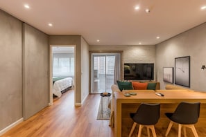 Ein moderner Wohnraum mit einem Holzesstisch, zwei Stühlen, einer Couch, einem Fernseher und einem Kamin.