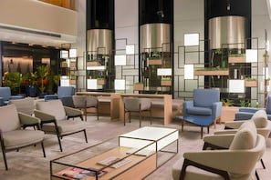 Eine moderne Lobby mit Sitzgelegenheiten, einem Couchtisch und dekorativen Pflanzen.