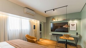 A modern hotel room with a bed, a chair, a small table, a TV, and a wall-mounted shelf. - Cyclinn a 400m do WTC Berrini Vila Olímpia #WB1711 (Berrini)