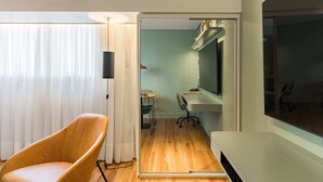 A modern room with a wooden floor, a large flat-screen TV, a comfortable chair, and a desk with a chair. - Cyclinn a 400m do WTC Berrini Vila Olímpia #WB1711 (Berrini)