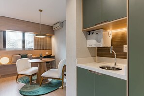 A compact kitchen with a built-in sink, a dining area with a round table and chairs, and a window with blinds. - Cyclinn a 400m do WTC Berrini Vila Olímpia #WB809 (Berrini)