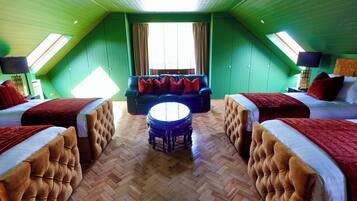 A room with two beds, a sofa, a round coffee table, and a large window.