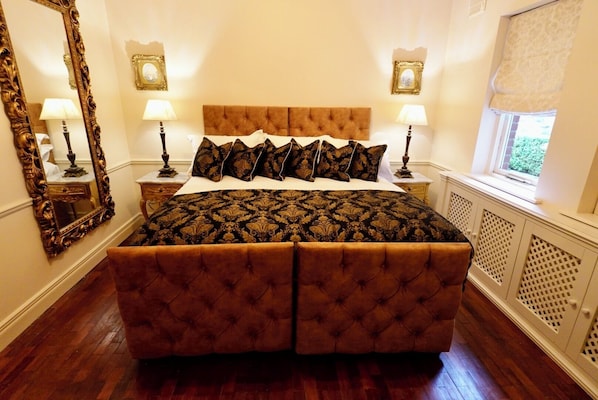 Un dormitorio con una cama grande, dos mesitas de noche con lámparas, un espejo grande y una ventana con vistas.