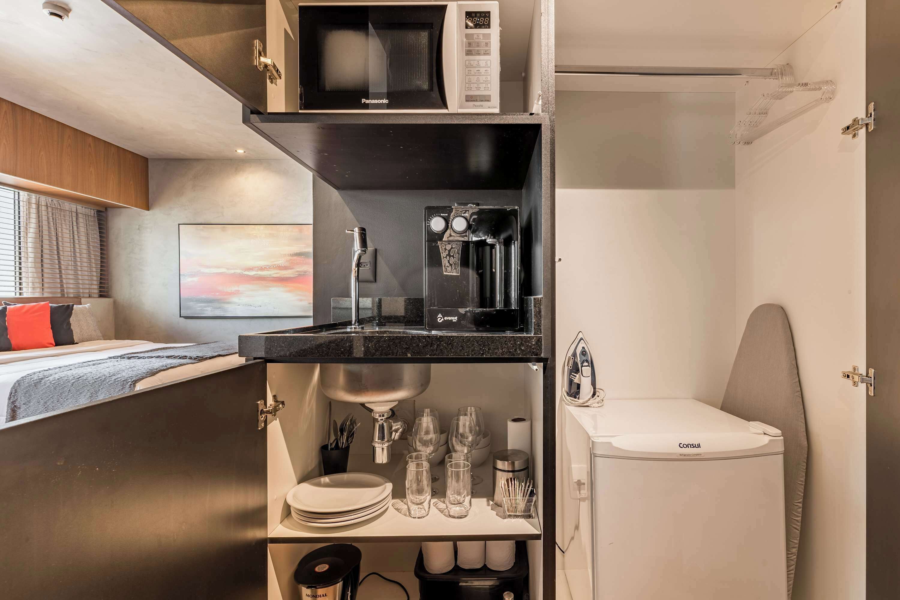 A compact kitchenette with a microwave, coffee machine, and a sink.