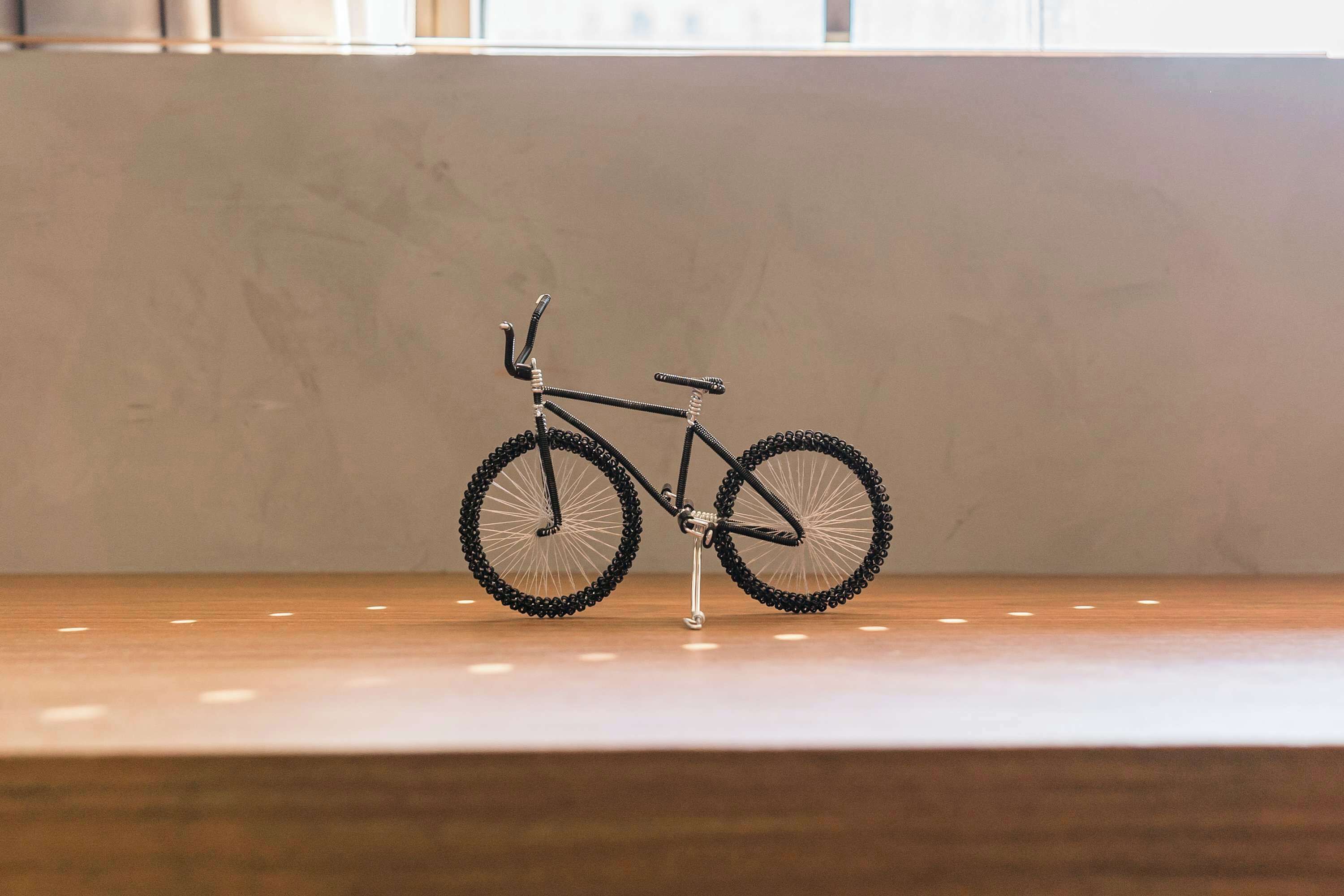 A bicycle on a wooden floor with a plain wall in the background.