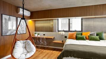 Un dormitorio moderno con una silla colgante, un escritorio y una cama con muchas almohadas.