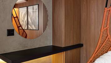 Una habitación moderna con un espejo circular, un estante negro, un revestimiento de pared de listones de madera, una hamaca colgante y un otomano redondo.