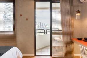Ein Schlafzimmer mit Bett, einer Schiebetür zum Balkon und einem Essbereich mit Tisch und Stühlen.