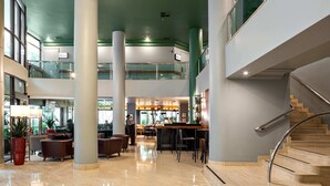 En rymlig entréhall med en svängd trappa, flera sittgrupper och en bar.