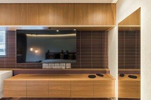 Ein modernes Wohnzimmer mit einem großen Flachbildfernseher, Holzschränken und einer eingebauten Bank mit Couchtisch.