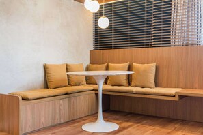 A corner seating area with a round white table, wooden paneling, and a window with blinds. - Cyclinn a 400m do WTC Berrini Vila Olímpia #WB1812 (Berrini)