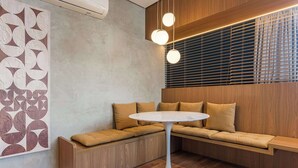 Un intérieur moderne avec un banc en bois, une table ronde et des luminaires suspendus.