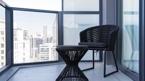 A balcony with a wicker chair and a small table, overlooking a cityscape. - #VN1811 | Cyclinn Vila Olímpia (Vila Olímpia)