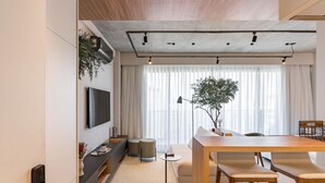 A modern living room with a sofa, a dining table, and a TV mounted on the wall. - #VN1811 | Cyclinn Vila Olímpia (Vila Olímpia)