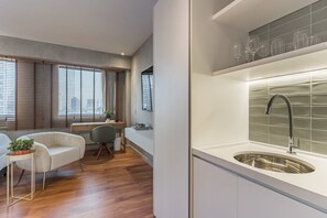 A modern kitchen with a stainless steel sink, wooden flooring, and a dining area with a white sofa and a small table. - #QL0603 | Cyclinn Faria Lima Pinheiros (Pinheiros)