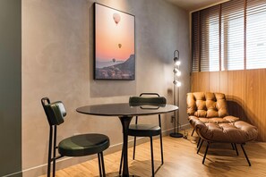 Ein Zimmer mit einem runden Tisch, zwei Stühlen, einem Ledersessel, einer Wandleuchte und einem gerahmten Bild von Heißluftballons.