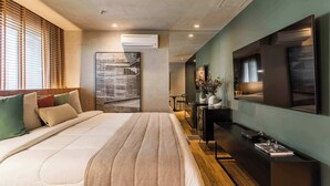 Una moderna camera d'hotel con un letto grande, una TV, una scrivania e vista sulla città.