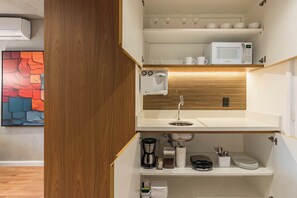A compact kitchenette with a microwave, coffee maker, and storage shelves. - Cyclinn a 400m do WTC Berrini Vila Olímpia #WB409 (Berrini)