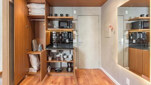 Una cucina compatta con elettrodomestici integrati, mobili in legno e una parete di fondo a specchio.