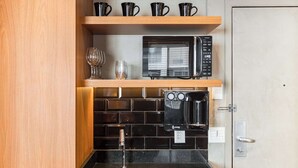Una piccola cucina accessoriata con forno a microonde, macchina del caffè e lavandino.