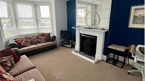 Een woonkamer met een open haard, een bank, een televisie en een eethoek.