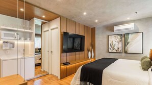 Une chambre moderne équipée d’un lit, d’une télévision, d’une cuisine intégrée et d’un dressing.