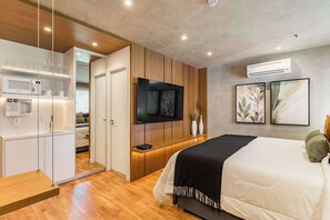 A modern bedroom with a bed, TV, built-in kitchen, and a walk-in closet. - #WP502 | Cyclinn Paulista Jardins (Jardim Paulista)