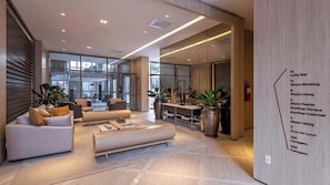 Eine moderne Lobby mit Sitzgelegenheiten, einem Empfangsbereich und einer Wand mit Zimmernummern und -bezeichnungen.