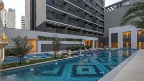 Ein modernes Hotel mit Dachpool, mehreren Balkonen und Sitzbereichen im Freien.