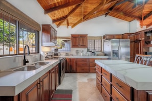 A kitchen with wooden cabinets, stainless steel appliances, and a large window. - Casa Coco -Luxury House (Provincia de Guanacaste)