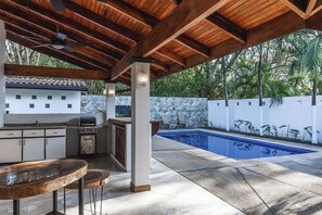An outdoor kitchen with a pool, wooden ceiling, and a stone wall. - Casa Coco -Luxury House (Provincia de Guanacaste)