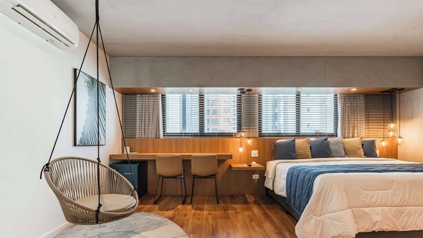 A modern bedroom with a bed, desk, chairs, and a hanging chair. - Cyclinn a 400m do WTC Berrini Vila Olímpia #WB202 (Berrini)