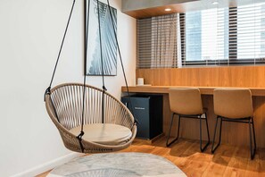 A modern kitchen with a hanging chair, a refrigerator, and a dining area with chairs. - Cyclinn a 400m do WTC Berrini Vila Olímpia #WB202 (Berrini)