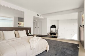 Ein modernes Schlafzimmer mit großem Bett, einem Trainingsbereich und minimalistischem Design.