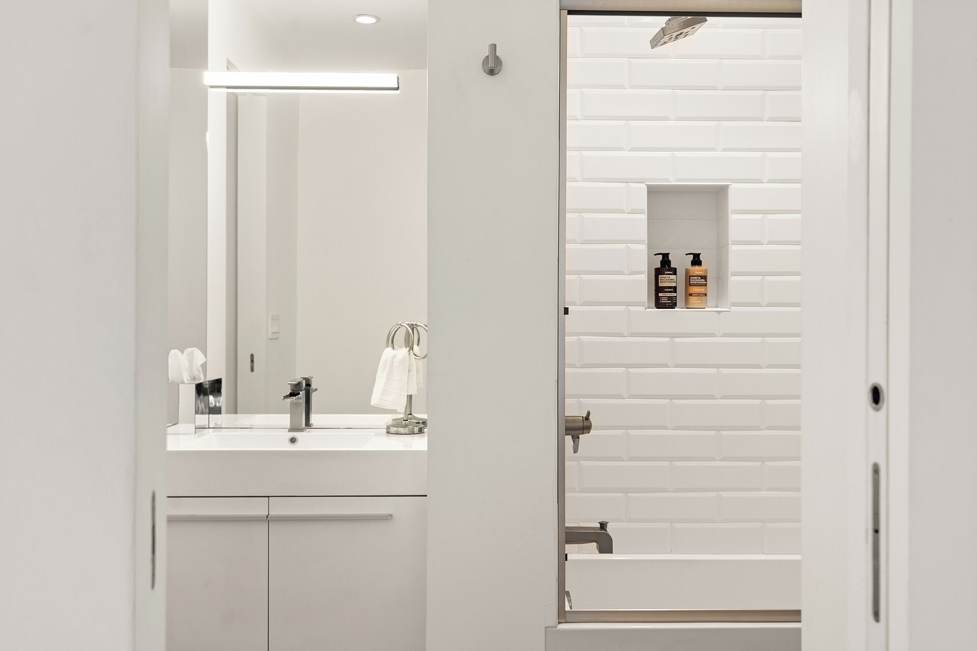 Een moderne badkamer met een witte wastafel, spiegel en handdoekrek.