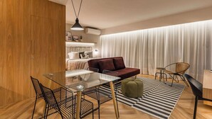 Un salon moderne avec une table à manger en verre, des chaises noires, un canapé rouge et un tapis à rayures.