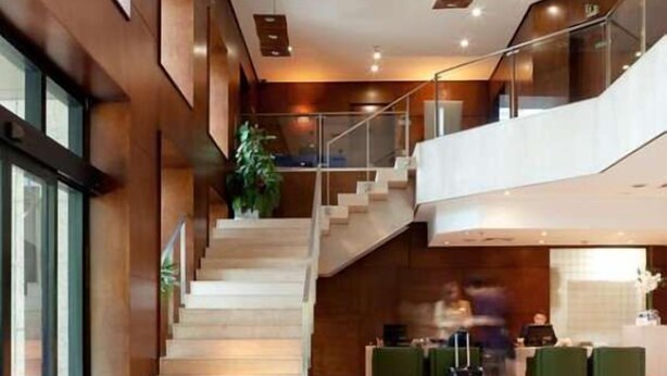 Un hall d’hôtel avec un escalier, un comptoir d’accueil et un espace salon.