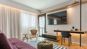 Un salon moderne avec un canapé, un pouf et un bureau avec des chaises.