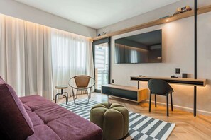 A modern living room with a sofa, ottoman, and a desk with chairs. - #EB806 | Cyclinn Brooklin Santo Amaro (Brooklin)