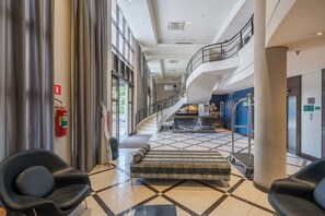 A spacious lobby with a high ceiling, a staircase, a fire extinguisher, and a seating area. - #QL1606 | Cyclinn Faria Lima Pinheiros (Pinheiros)