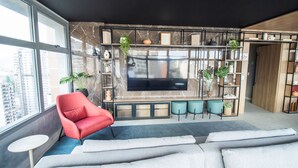 En moderne stue med et stort fjernsyn, en rød lænestol og en sofa.
