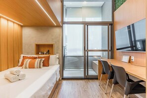 A modern hotel room with a bed, a desk, and a TV. - Studio Completo a 100m do Metrô Brooklin | HM205 (Brooklin)
