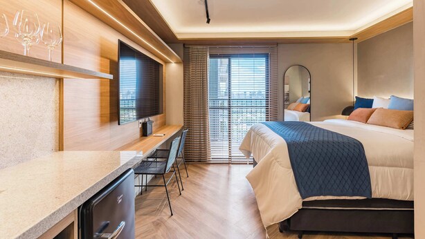 Ein modernes Hotelzimmer mit Bett, Schreibtisch, Stühlen und Fernseher.